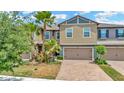 Inviting two-story townhouse with a brick-paved driveway, attached garage, and lush landscaping at 28516 Tranquil Lake Cir, Wesley Chapel, FL 33543