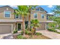 Inviting two-story townhouse with a brick-paved walkway, attached garage, and lush landscaping with palm trees at 28516 Tranquil Lake Cir, Wesley Chapel, FL 33543