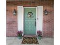 Inviting brick entryway with a green door, decorative wreath, potted plants, and charming lanterns for a cozy welcome at 3537 12Th N Ave, St Petersburg, FL 33713