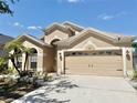 Tan home with a two-car garage and well-kept landscaping and concrete driveway at 408 Delwood Breck St, Ruskin, FL 33570