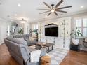 Inviting living room featuring hardwood floors, a large entertainment center, and a ceiling fan at 4689 Wandering Way, Wesley Chapel, FL 33544