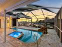 Tranquil screened pool and spa area with stone waterfall feature, sunset views, and covered patio at 5818 Cruiser Way, Tampa, FL 33615