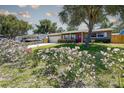 Inviting single-story home featuring a lush front yard filled with colorful flowers and a vibrant red front door at 8497 137Th St, Seminole, FL 33776