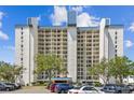 Modern condo building with multi-story balconies and parking in front of lush landscaping at 9425 Blind Pass Rd # 802, St Pete Beach, FL 33706