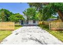 A cozy home is surrounded by newly installed wood fences, manicured lawn, and a modern driveway at 10011 N Annette Ave, Tampa, FL 33612
