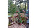 Wooden deck with a potted plant with pink and red flowers overlooking a lush backyard, perfect for outdoor relaxation at 10502 Atlee St, New Port Richey, FL 34654
