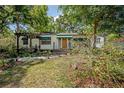 Quaint single-story home with inviting front porch and a lush front yard with mature trees at 1211 E Park Cir, Tampa, FL 33604