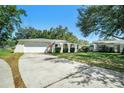 Single-story home with a front-facing two car garage, arched doorway, and manicured lawn at 135 Rodney Ct, Palm Harbor, FL 34684