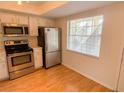 Kitchen featuring stainless steel appliances, white cabinetry and wood flooring at 1375 Doolittle Ln # 101, Dunedin, FL 34698