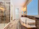 Beautiful bathroom features a soaking tub, frameless glass shower, and stylish wood-look tile flooring at 1723 Whitewillow Dr, Wesley Chapel, FL 33543