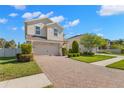 Charming two-story home featuring a manicured lawn and brick-paved driveway at 19487 Roseate Dr, Lutz, FL 33558