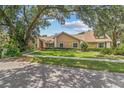 Inviting one-story home with a sprawling front lawn framed by mature trees and verdant landscaping at 6407 E 112Th Ave, Temple Terrace, FL 33617