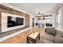 Modern living room featuring wood accent wall, open to kitchen with wood floors and neutral tones at 847 Highland N St, St Petersburg, FL 33701