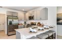 Modern kitchen features stainless steel appliances, quartz countertops, and an island with seating at 13253 Tropical Breeze Way, Hudson, FL 34669