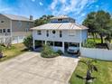 Aerial view of stilt home with metal roof, large driveway, and lush landscaping at 13974 75Th Ave, Seminole, FL 33776