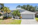 Attractive one-story home with a grey exterior, arched windows, a two-car garage and beautiful landscaping at 18013 Palm Breeze Dr, Tampa, FL 33647