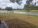 Spacious backyard with a white picket fence and a serene view of the pond at 23015 Mayfair Rd, Land O Lakes, FL 34639