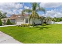 Beautiful home featuring lush green lawn, landscaped garden beds, and a lovely palm tree at 25830 Crippen Dr, Land O Lakes, FL 34639