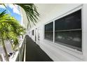 Exterior building hallway showing unit 208, dark gray flooring, white railings and walls, and mature palm trees at 3128 59Th S St # 206, Gulfport, FL 33707