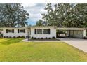 Front view of home with a well-manicured lawn, a carport, and lush landscaping, creating a welcoming curb appeal at 403 Westbrook Ave, Brandon, FL 33511