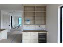 Bright bar area with custom built-in shelving, modern wine fridge and marble backsplash at 501 W Ross Ave # 2, Tampa, FL 33602