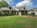 Charming single-story home with dormer windows, a lush lawn, mature trees, and well-maintained landscaping at 8361 Cofield Ln, Spring Hill, FL 34608