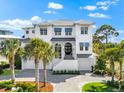 Beautiful two-story white home with a black front door, complemented by tropical palm trees and manicured lawn at 885 Seaview Cir # 20, Crystal Beach, FL 34681