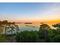 Scenic water view at sunset with trees in foreground and a pier in the distance at 885 Seaview Cir # 20, Crystal Beach, FL 34681