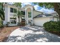 Attractive two-story home featuring a front-facing garage, mature landscaping, and natural light at 9315 Knightsbridge Ct, Tampa, FL 33647