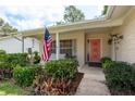Charming front porch featuring an American flag, seating area, and view of lush front yard landscaping at 10516 Mira Vista Dr, Port Richey, FL 34668