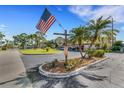 Community entrance with a DARWHO 55+ sign, American flag, and beautifully landscaped grounds at 120 Cedarwood Cir # 120, Seminole, FL 33777