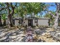 Charming single-story home with mature trees and a welcoming entrance with a gray door at 1247 21St St, Sarasota, FL 34234