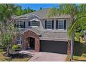 Two-story home featuring a stone-accented entry, dark-stained garage door, and professionally landscaped front yard at 12935 Solola Way, Trinity, FL 34655
