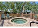 Inviting community hot tub surrounded by a fence and mature trees at 1486 Mahogany Ln # 703, Palm Harbor, FL 34683