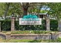 Community sign for Laurel Oaks surrounded by brick columns, black fence, and landscaping at 1486 Mahogany Ln # 703, Palm Harbor, FL 34683