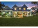 Beautiful two-story home featuring a cozy front porch, lush lawn, and warm exterior lighting at twilight at 18929 Crescent Rd, Odessa, FL 33556