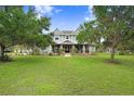 Inviting two-story home with a charming front porch and sprawling green lawn, framed by mature trees at 18929 Crescent Rd, Odessa, FL 33556