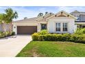 Inviting single-story home with a well-kept lawn, a brown garage door, and landscaped shrubs at 2644 Leafwing Ct, Palm Harbor, FL 34683