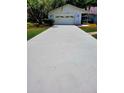 Long, paved driveway leading to a two-car garage, surrounded by green lawns and mature trees at 3529 Tanglewood Trl, Palm Harbor, FL 34685