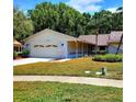 Single-story home with a two-car garage, well-maintained lawn, and beautiful landscaping at 3529 Tanglewood Trl, Palm Harbor, FL 34685