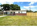 A cozy one-story house showcasing a new wooden fence, brick facade, and a green lawn at 8310 Croton Ave, Tampa, FL 33619