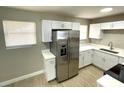 A modern kitchen showcasing stainless steel refrigerator, white cabinets, and wood-look floors at 8310 Croton Ave, Tampa, FL 33619