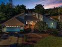 Well-lit dusk view of home showing landscaping, brick walkway and stone pillar accents at 833 Lakeside Ter, Palm Harbor, FL 34683