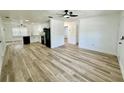 Open-concept living room with light-colored hardwood flooring, ceiling fan and natural light from windows at 9230 Wood Dr, Hudson, FL 34667