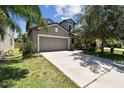 Charming two-story home featuring a neutral gray exterior, two-car garage, well-manicured lawn and mature landscaping at 10148 Rose Petal Pl, Riverview, FL 33578