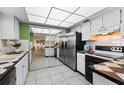 Efficient kitchen featuring neutral cabinets, a mirrored wall, stainless refrigerator and black appliances at 1250 S Pinellas Ave # 405, Tarpon Springs, FL 34689