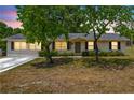 Well-lit single-story home with a manicured lawn and classic curb appeal at dusk at 27343 Warner Ave, Brooksville, FL 34602