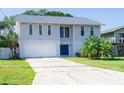 Two-story home with a two-car garage, blue front door, and landscaped front yard at 320 Crosswinds Dr, Palm Harbor, FL 34683