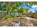 Private backyard featuring a stone fire pit, gravel ground cover, mature shade trees, and a wood fence surround at 4330 7Th N Ave, St Petersburg, FL 33713