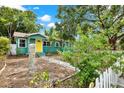 Landscaped turquoise home with a bright yellow front door, charming stone address post, and white picket fence at 4330 7Th N Ave, St Petersburg, FL 33713